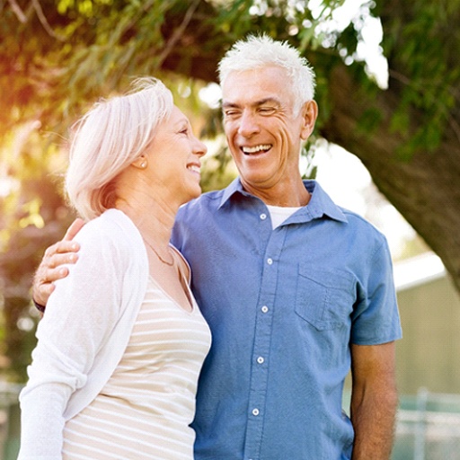 Older couple smiling together outside while sun is out