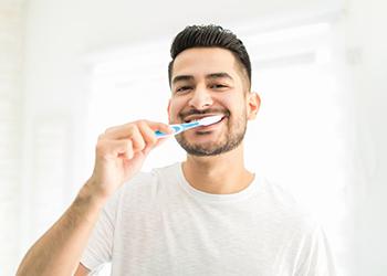 a man smiling and brushing his teeth in the morning