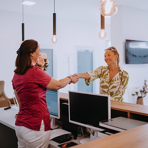 Dental receptionist shaking hands with patient