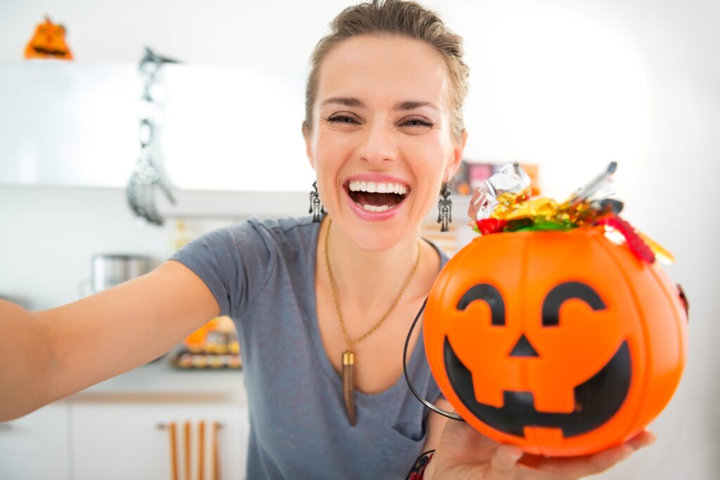 Woman smiling while holding bucket of Halloween candy