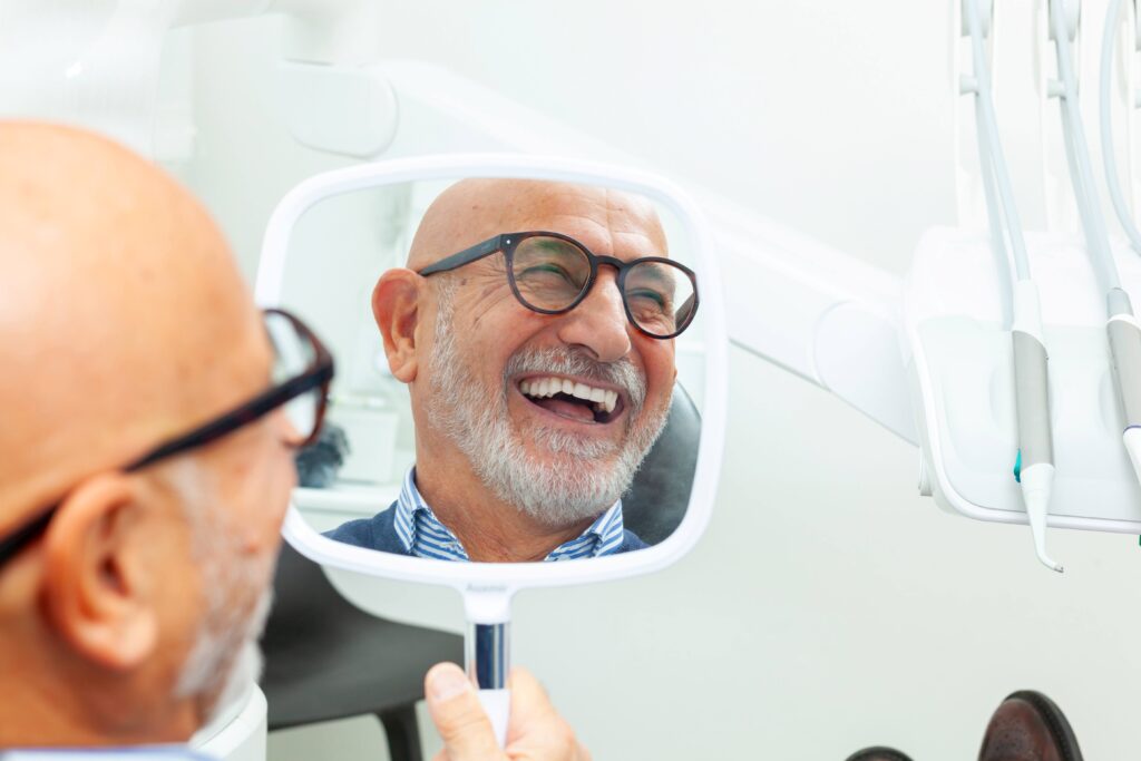 Man smiling in reflection of handheld mirror